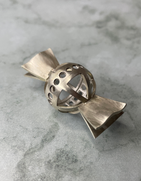 Réalisée durant mon stage à la Bijouterie Gourret, cette pièce se compose de sept éléments. Au centre, un anneau comporte 20 mises en pierre, toutes mises à jour. Autour de cet anneau, deux demi-sphères formées par emboutissage, puis repercées pour créer des motifs en quartiers d’orange. Enfin, quatre trapèzes positionnés aux extrémités ont été mis en forme afin de donner un aspect de papillote.